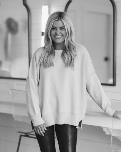 woman wearing sweater and leggings smiling standing in bathroom