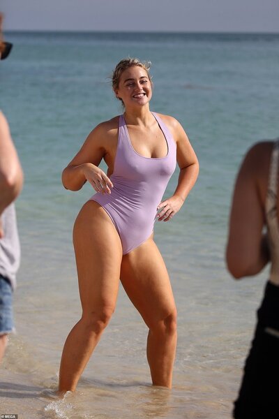 Iskra is smiling and having fun at a beach, with her feet in the water.