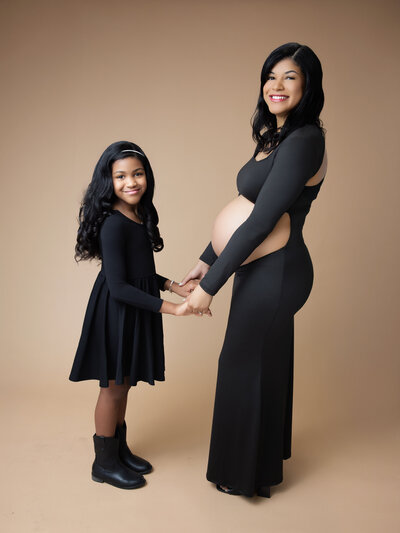 a pregnant mom holding hands with her daughter