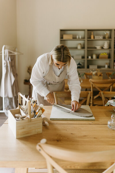 Kaksi valkoista lautaste ja yksi ruskea lautanen päällekkäin, joiden pällä on vaalea kuppi 