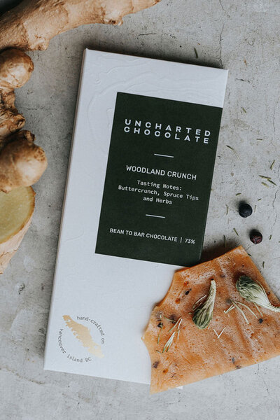 Uncharted Chocolate's Woodland Crunch bar with forest-inspired packaging and ingredients like ginger, herbs, and spruce tips, handcrafted on Vancouver Island