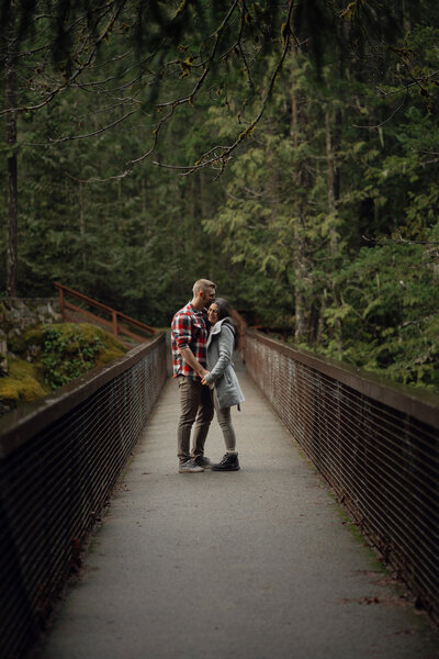 Couple on a bridge over Englishman River falls during their engagement session