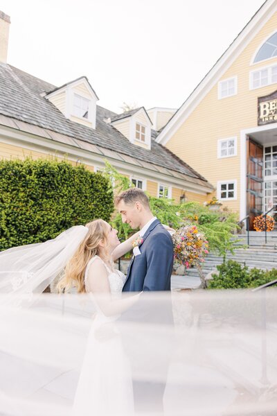 Bride and groom hugging while the veil blows in front of them during their Bedford Village Inn Wedding