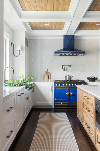 bright white kitchen with wood panel accents on the ceiling and dark blue stove