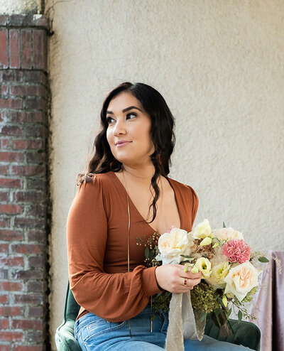 A woman holding a flower bouquet looking off to the side.