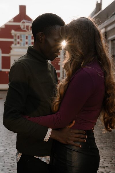 Een koppel omarmt elkaar voor een rood bakstenen gebouw, vastgelegd door fotograaf Julia de Groot tijdens hun koppel fotoshoot