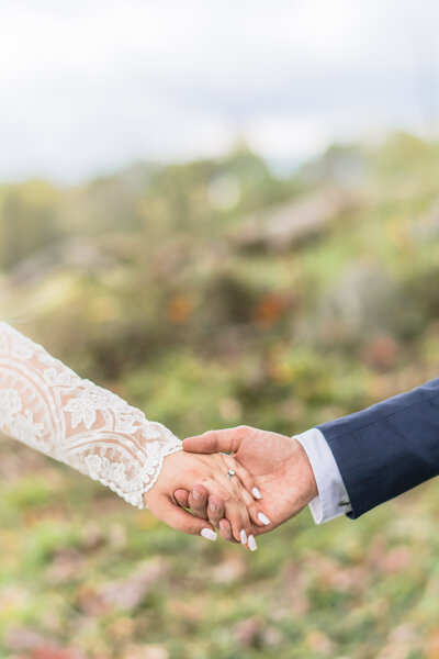 Couple holding hands in a bright field of flowers.