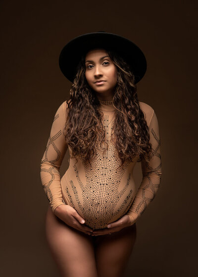 Modern studio maternity portrait of beautiful  woman in bodysuit with rhinestones