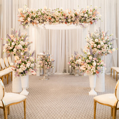 Large pastel arrangements and suspended arch at a Four Seasons wedding ceremony. 