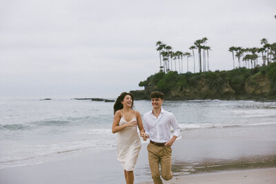 a couple running on the beach in California during their documentary engagement session