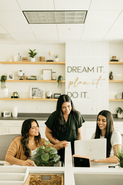 Young women dressed in business casual attire looking at a laptop