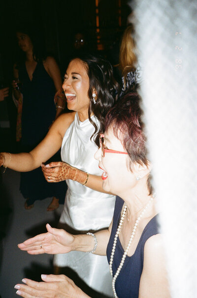 Bride laughing and dancing with guests during a cultural wedding weekend at Le Belvédère in Quebec — documentary-style celebration photography filled with emotion and movement.