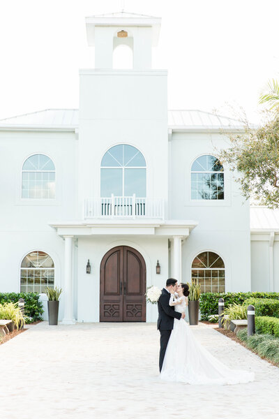 bridal couple sharing a kiss in front of wedding chapel