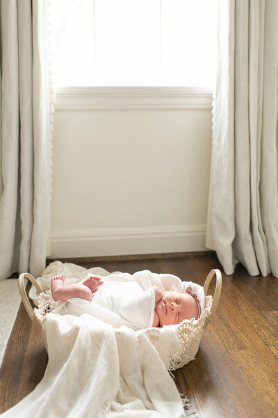 Newborn baby wrapped in a white blanket captured by Moments in Light Photography