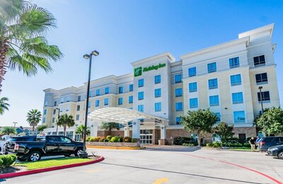 Exterior of Holiday Inn in Webster, Texas on a sunny day with a palm tree in front