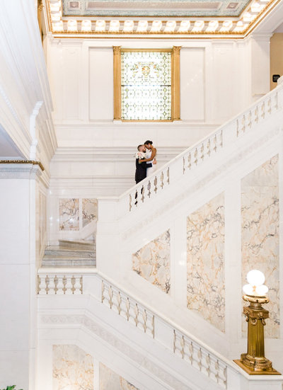 Bride and groom on grand white marble staircase at the kimpton hotel monaco