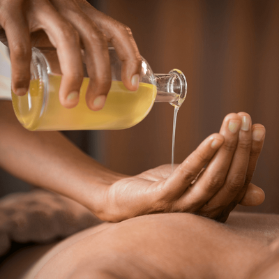 masseuse pouring oil into hand for massage