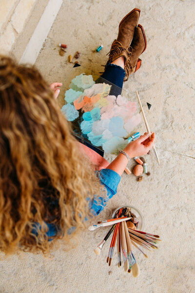 Nature-inspired artist and author with paintbrushes, blending gardening and creativity