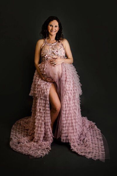 Pregnant woman wearing a pink gown in a studio in Stamford, CT for a maternity session.