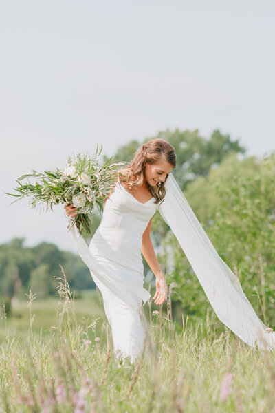 Minneapolis bride walks through grass meadow