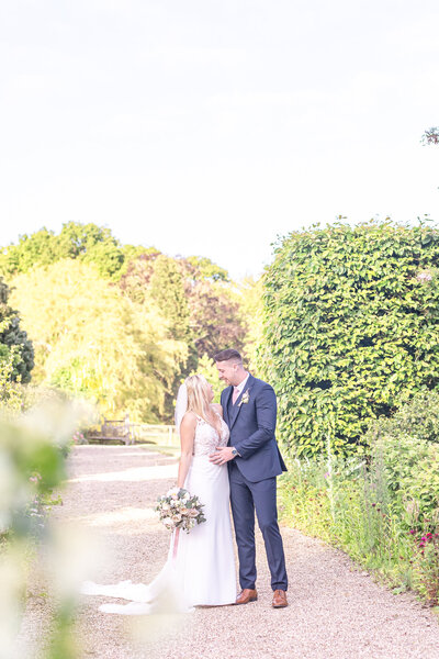 Bride and groom kissing in front of Abbeywood Estate wedding venue in Cheshire