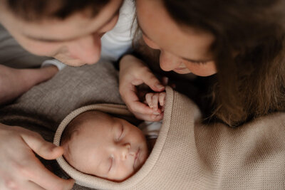 Koppel kijkt naar pasgeboren baby tijdens newborn fotoshoot door Julia de Groot Fotografie