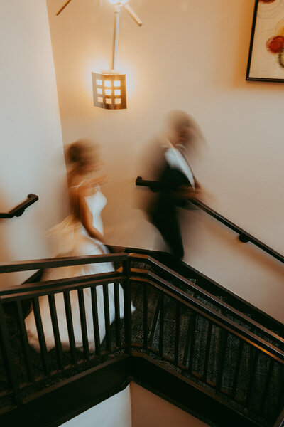 woman in white and man in black walk down in blurry staircase photo
