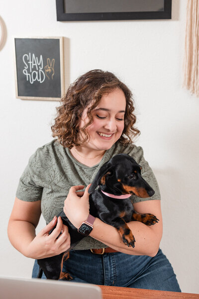woman smiling and looking down at a small dog in her arms