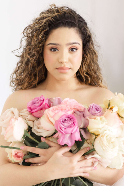 bride holding a bouquet of blush and cream roses