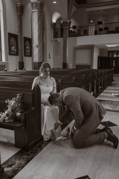 Groom helping bride at NDSU Newman Center wedding in Fargo, North Dakota.