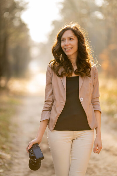 Vrouw met camera kijkt lachend opzij bij de Ginkelse heide