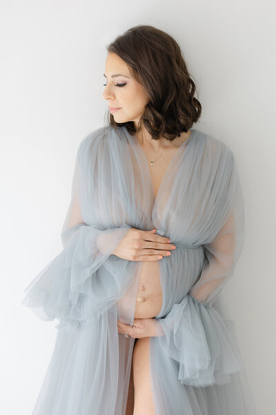 Pregnant woman holding belly tulle blue dress maternity photos