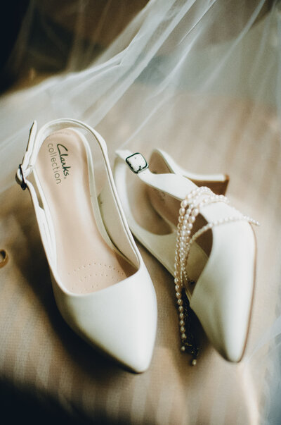 Black and white photo of groom standing against a wall and fixing his tie