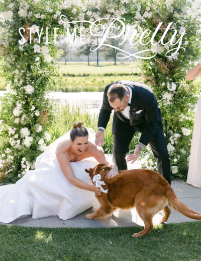 ride and groom petting their golden retriever during their outdoor wedding ceremony.