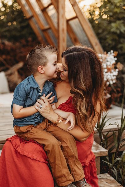 A mother and her son rubbing noses together and giggling.