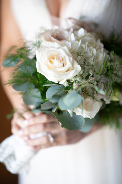 An Austin-based wedding photographer captures the bride holding a bouquet of white roses and eucalyptus.