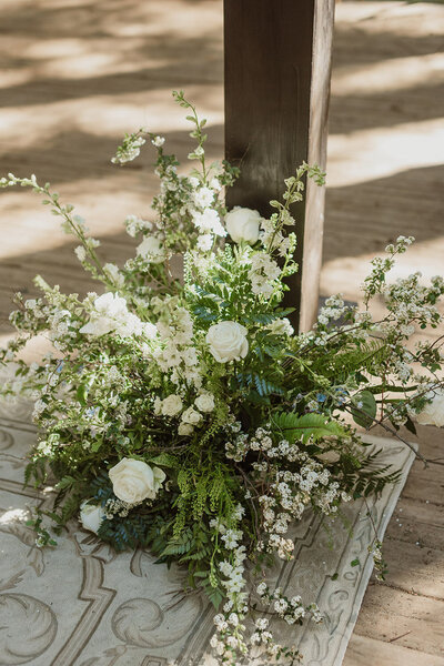 White rose and greenery floral arrangement on floor