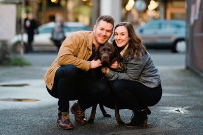 Engaged couple celebrated upcoming wedding with a Seattle engagement photographer in Ballard, with bricks and ivy and a labrador dog