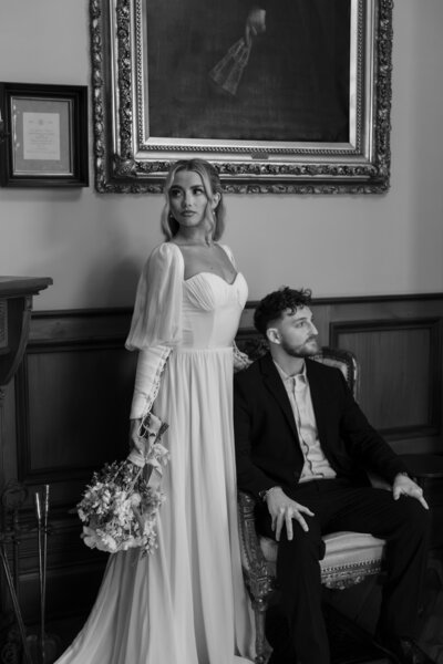Bride and groom posing elegantly inside their wedding venue, surrounded by beautiful decor, captured in a timeless and romantic portrait.