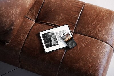 A phone and iPad sitting on a leather couch with a website pulled up on them.
