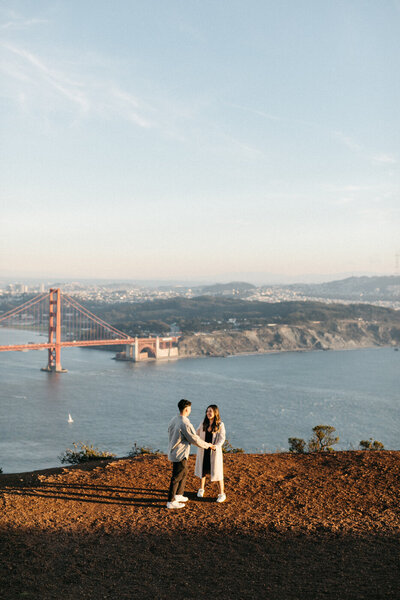 couple getting engaged with golden gate bridge and san francisco in the background