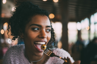 woman smiling while eating an olive from a fork to keep her blood sugar happy