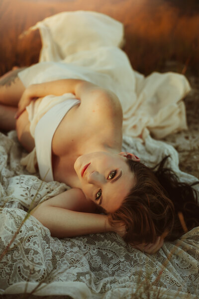 intimate pregnancy potrait of a women laying on a vintage lace blanket