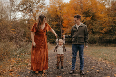 Fall family photographs in Wisconsin are a must. This image shows a family of three playing with their son at a park in the fox valley.