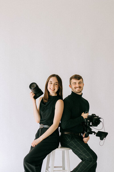 man and woman holding cameras