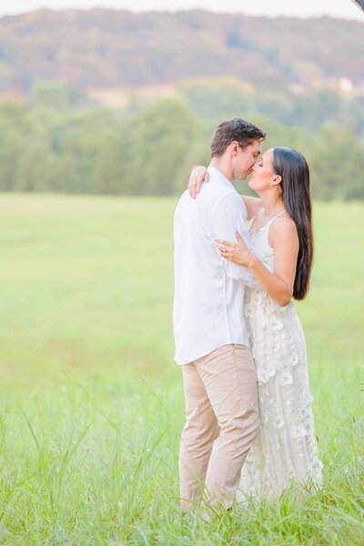 A couple kisses with mountains in the background on the Carolina Country Wedding lawn.