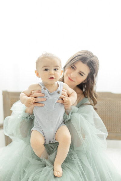 A mom holding her baby boy as she sits on a chair in a DFW photography studio.