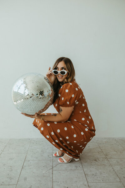 woman smiling holding a disco ball