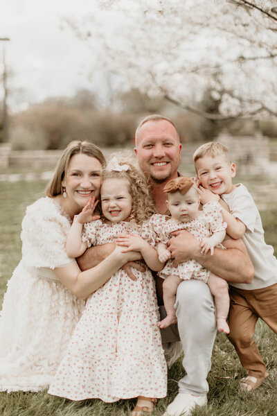 Mom, dad, and three kids wrapped up in a big, playful family hug.