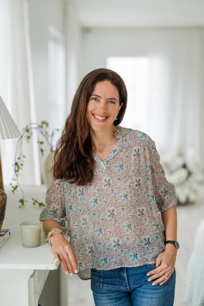 woman standing in front if white door and playing with camera cap